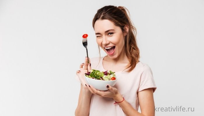 красивая девушка кушает салат, держит вилку в руках
