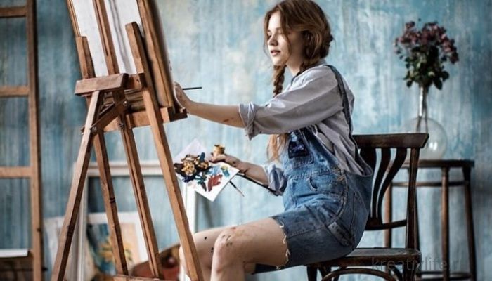 Девушка рисует красками на холсте картину