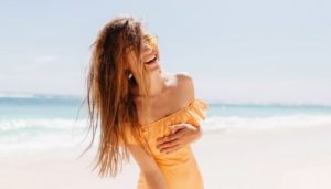 Женщина смеется в купальнике на пляже