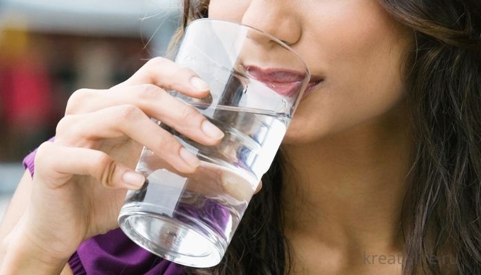 Девушка пьет стакан воду перед едой