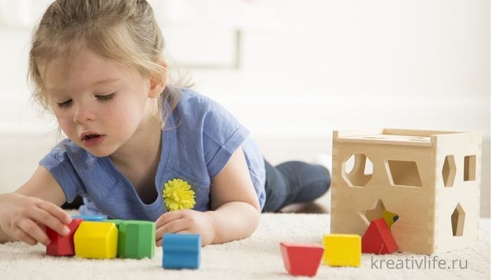 Девочка играет развивающими игрушками из дерева 