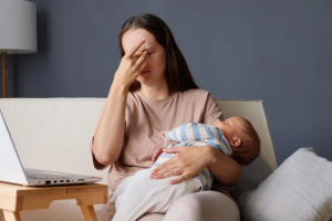 Молодая уставшая мама с младенцем на руках